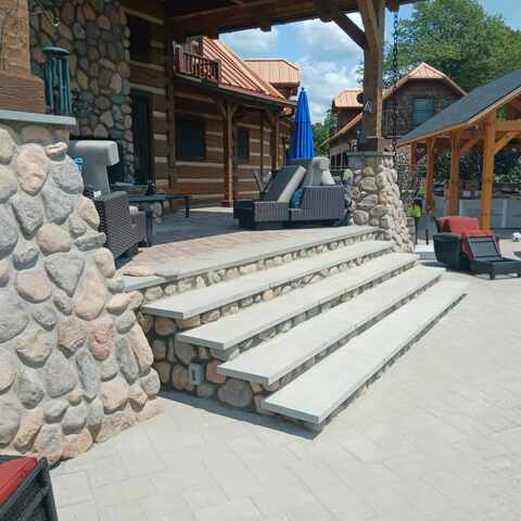 River rock columns and stone steps leading to a cabin patio