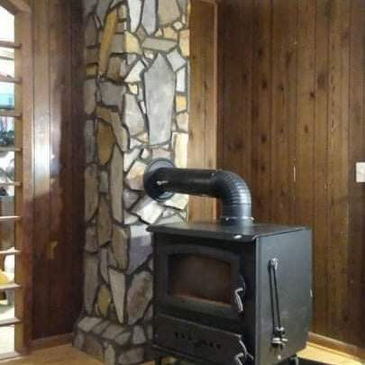 Finished stone chimney surround behind a wood stove