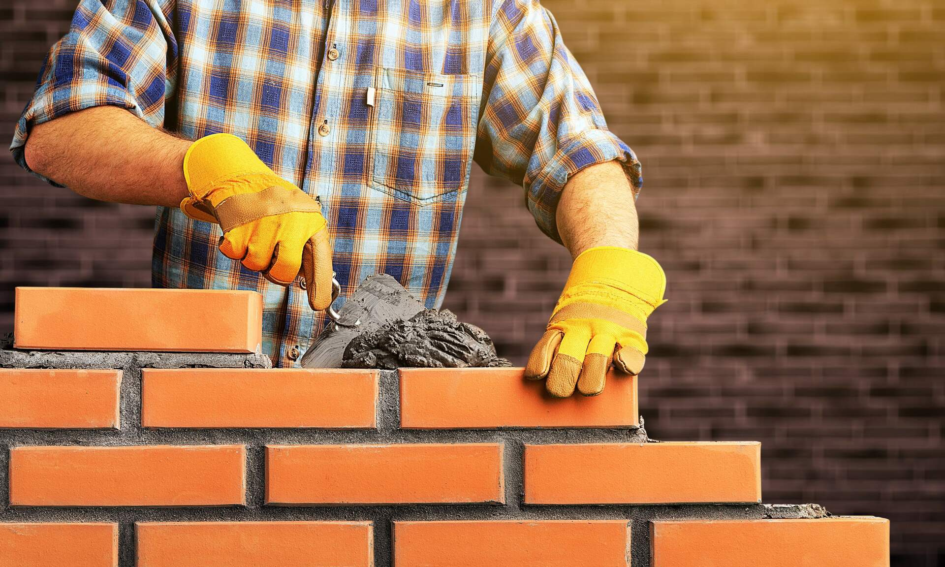 Mason laying a course of brick with a trowel and mortar