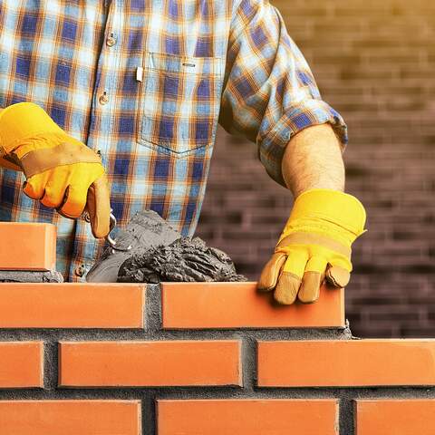 Mason spreading mortar while laying a brick wall
