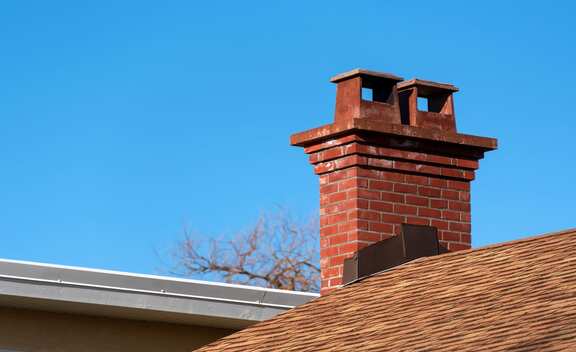 Brick chimney rising above a shingled roof